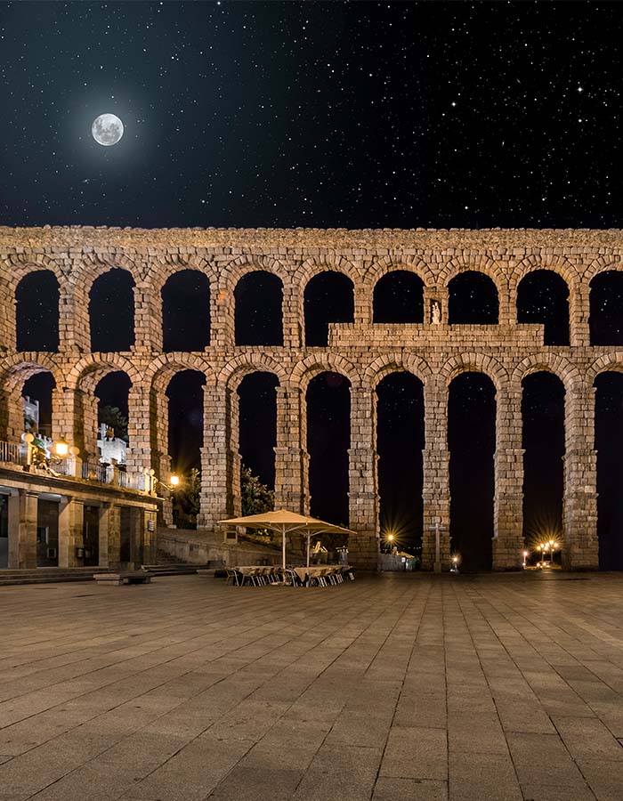 vista alargada del acueducto de segovia por la noche bajo la luna ciudad de el palacio de segovia | El Palacio de Segovia